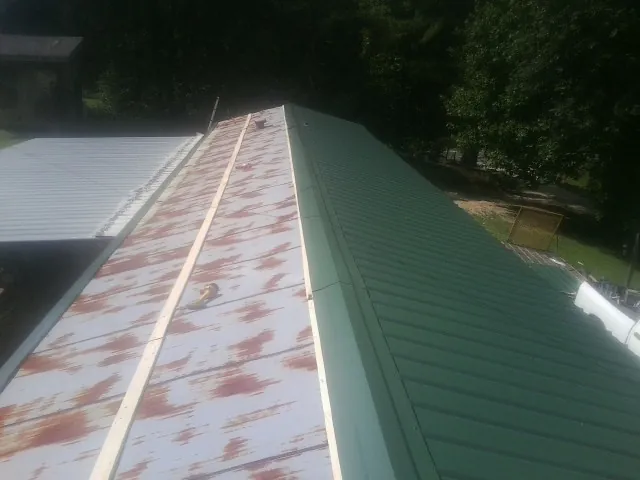 Old rusted panels beside newly installed green metal roofing — Wind Damage Roof Repair by Roofing Brothers in Sebring
